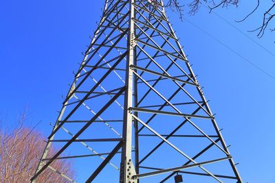 Low angle view of electricity pylon against clear blue sky
