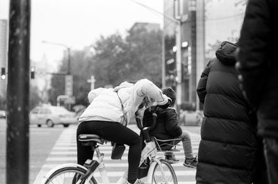 Rear view of people riding bicycle on street in city