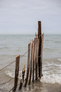 Wooden posts on beach against sky