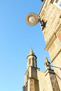 Low angle view of clock tower amidst buildings against clear sky