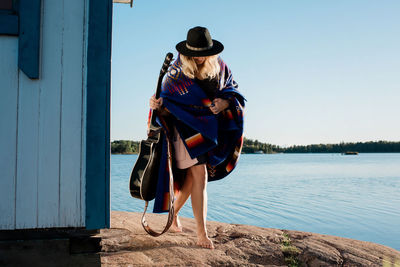 Woman wrapped in a blanket holding her guitar at the beach