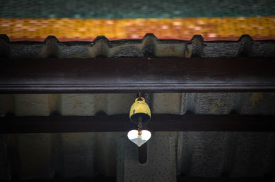 Low angle view of illuminated light bulb hanging on wall