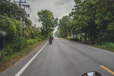 Rear view of person riding motorcycle on road