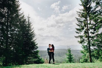 Side view of young couple standing face to face in forest