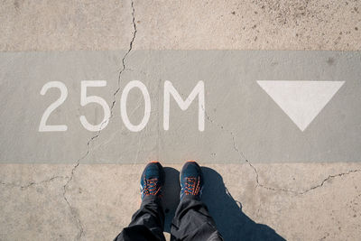 Low section of person standing by text on cracked road