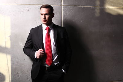 Portrait of a young man standing against wall