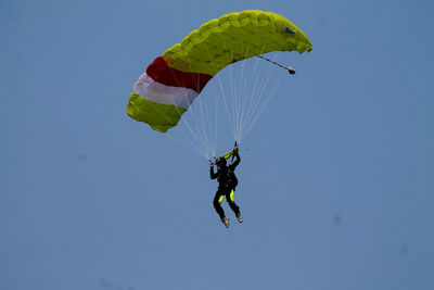 Low angle view of man paragliding against clear sky