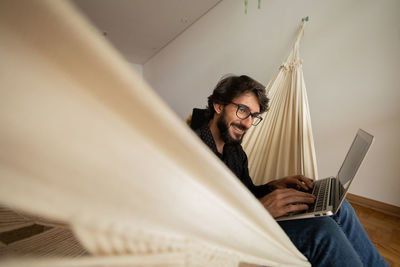 Young man  black glasses working with laptop on a white hammock notebook for working. home office