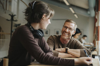 Happy professor discussing with student in library at university