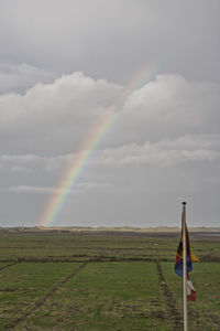 Scenic view of field against rainbow in sky