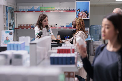 Side view of man using mobile phone while standing in store