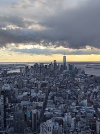 Aerial view of buildings in city against cloudy sky