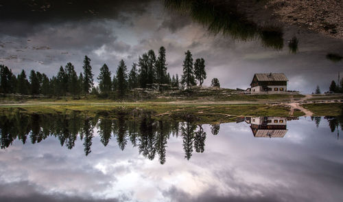 Upside down image of house and trees reflecting in lake