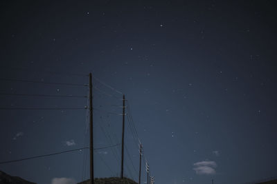 Low angle view of electricity pylon against sky at night