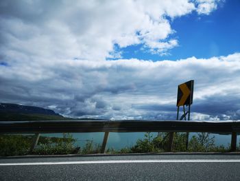 Road sign against cloudy sky