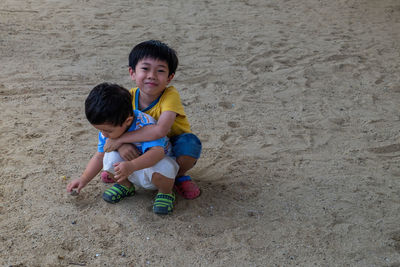 Cute boy playing with toy on sand