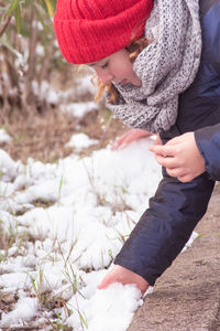 Midsection of woman holding snow on field