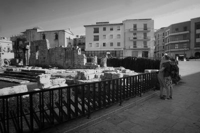 Rear view of woman on retaining wall against city