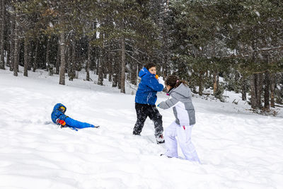 Friends playing in snow on field during winter