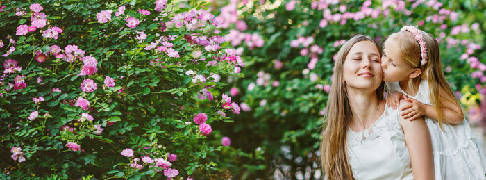 Portrait of young woman standing against plants