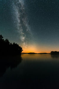 Scenic view of lake against star field in sky at sunset
