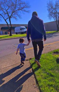 Rear view of boys walking on sidewalk