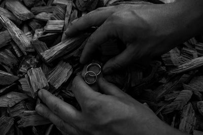 Cropped hands of man holding rings on wood