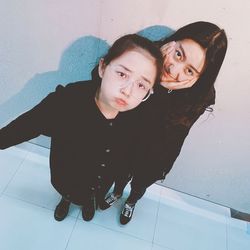 High angle portrait of siblings standing against wall