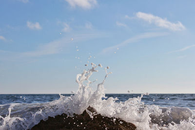 Waves splashing on shore against sky