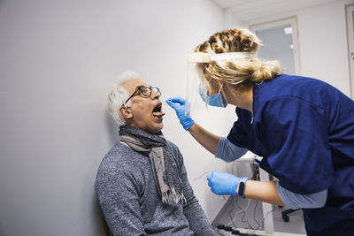 Female doctor performing covid-19 swab test on senior man