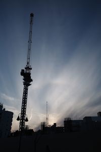 Low angle view of silhouette cranes against sky