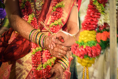 Cropped image of groom holding bride hand during wedding ceremony