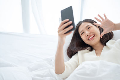 Young woman using mobile phone while lying on bed