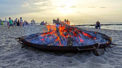 Panoramic view of people on beach against sky during sunset