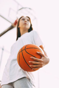 Close-up of a basketball in the hands of a young girl in sportswear