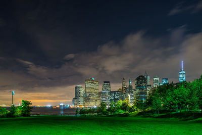 Illuminated cityscape against cloudy sky