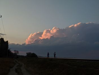 Silhouette people standing on field against sky during sunset
