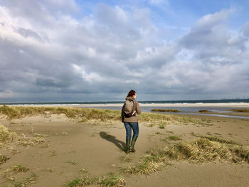 Rear view of man on beach against sky