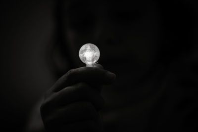 Cropped hand holding lighting equipment against black background