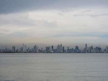 Sea and buildings in city against sky