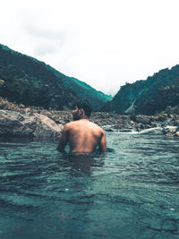 Rear view of shirtless man in water