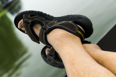 Low section of man wearing sandals in boat on lake