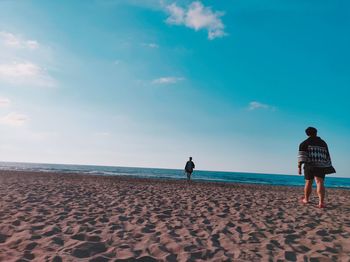 Rear view of women on beach against sky