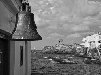 Church buildingand bell by sea against sky