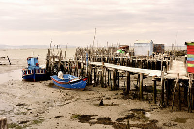 Boats moored on beach against sky during sunset