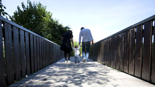 Rear view of parents walking with son on footbridge