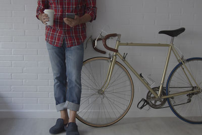 Hipster man with mobile phone and coffee next to bike