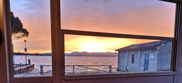 Buildings by sea against sky during sunset