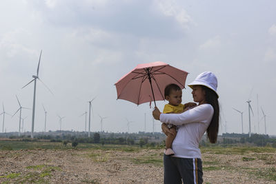 A young mother and her lovely little daughter are at a windmill field.