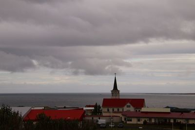 Buildings by sea against sky